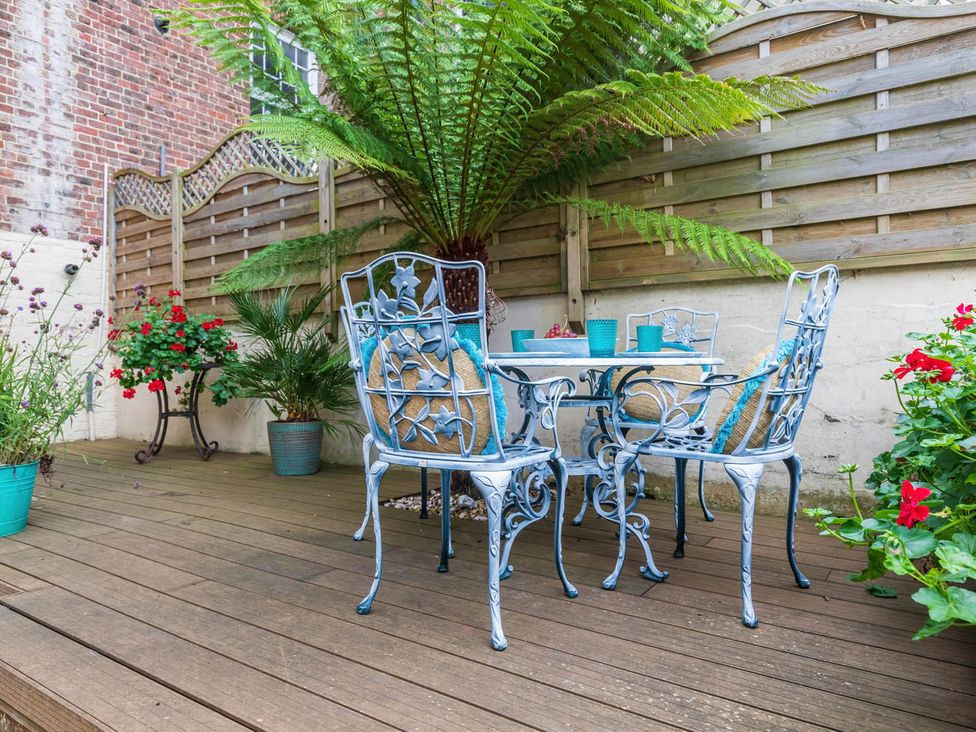 A garden with a table and chairs surrounded by plants at Seafront Apartment Private Garden Free Parking Littlehampton