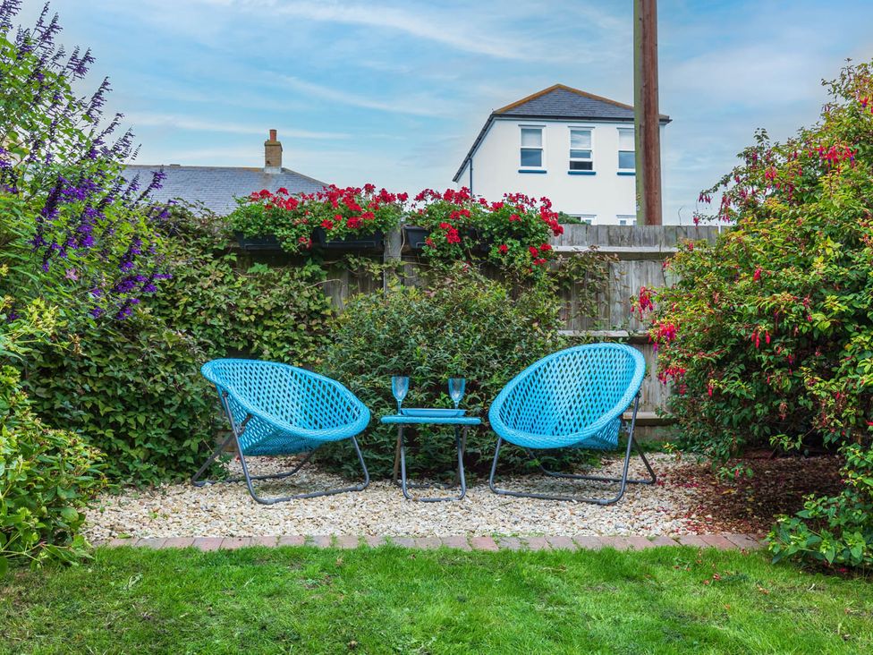 A garden with blue chairs and a table at Seafront Apartment Private Garden Free Parking in Littlehampton