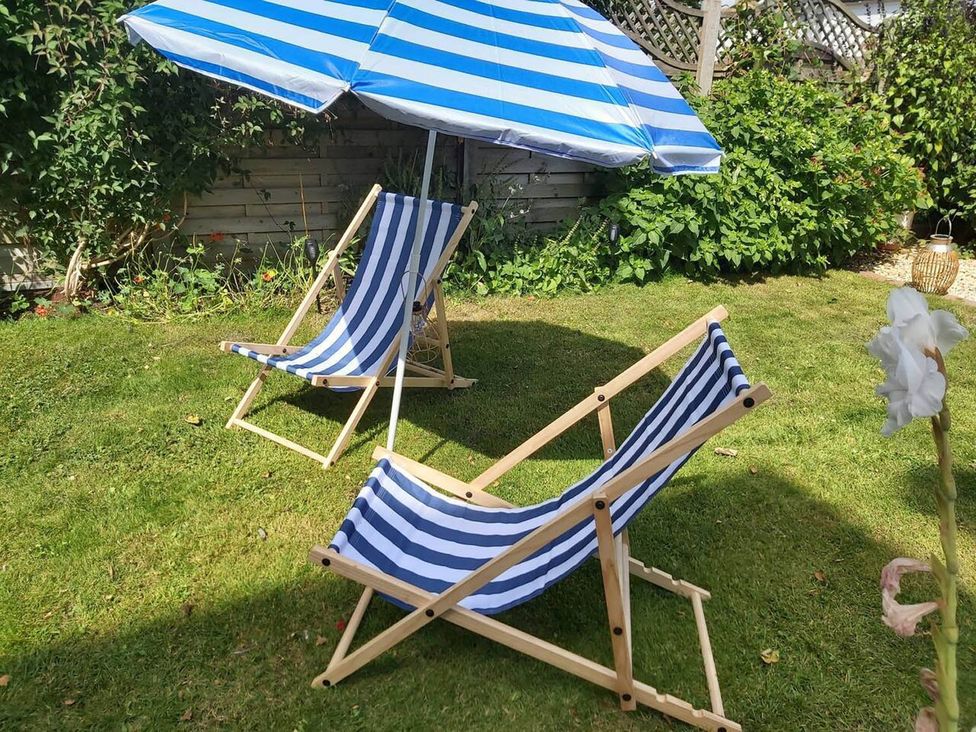 Two deck chairs and an umbrella in a garden at Seafront Apartment Private Garden Free Parking Littlehampton