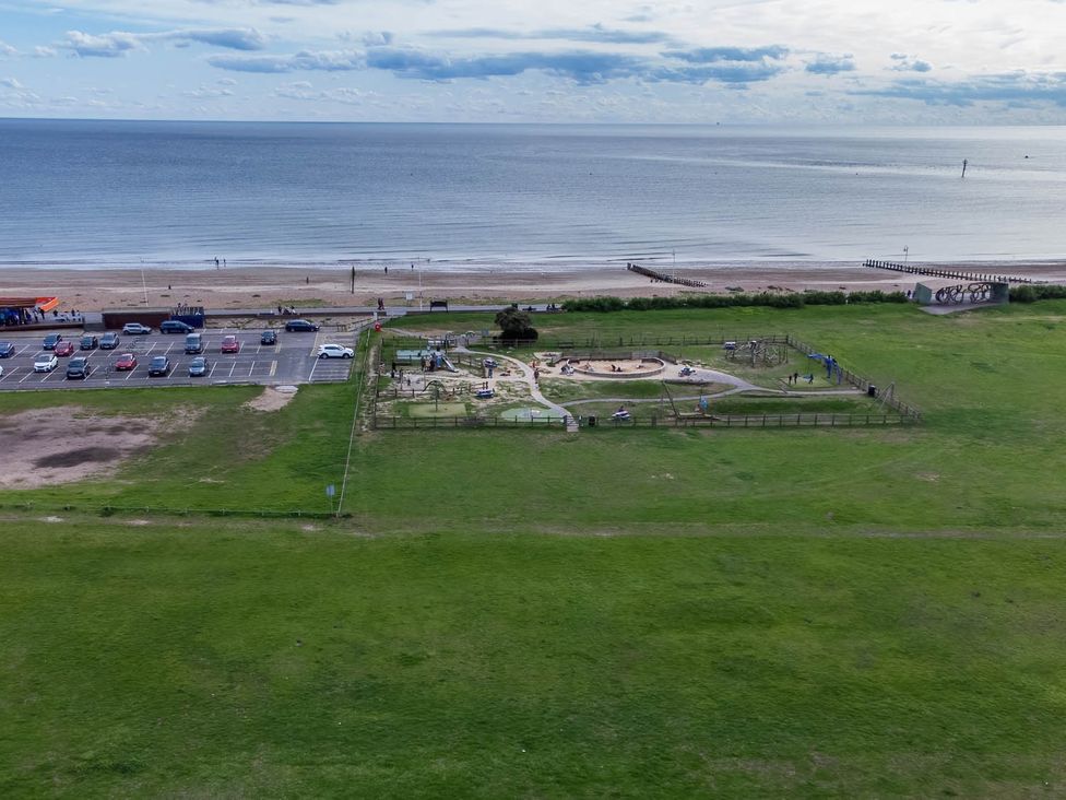 An outdoor area with a beach, playground, and parking at Seafront Apartment Private Garden Free Parking in Littlehampton