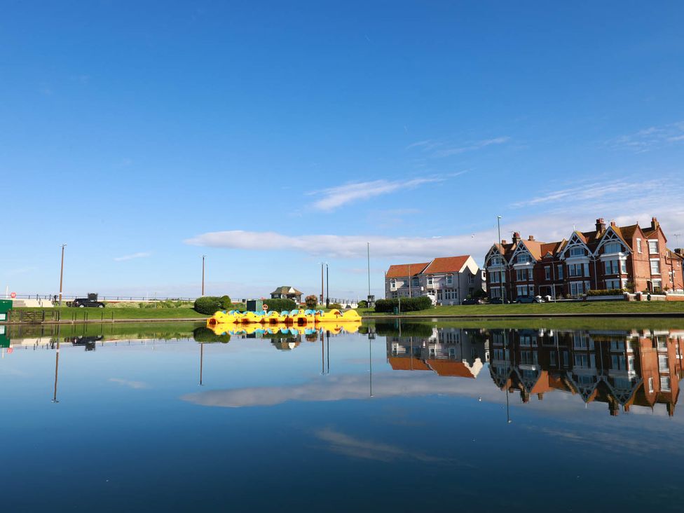 View of houses and paddle boats reflected in water at Seafront Apartment Private Garden Free Parking Littlehampton