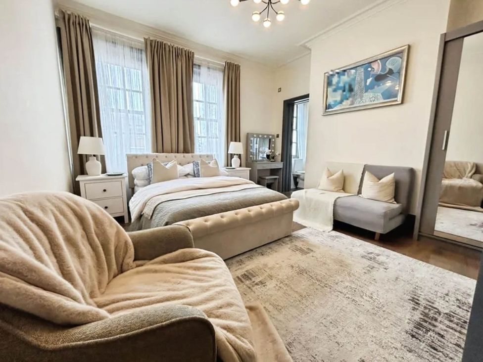 A bedroom with a bed, sofa, and mirror at 3 Bedrooms in Central Tunbridge Wells