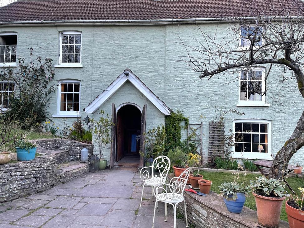 An outdoor area with a house entrance, chairs, and plant pots at The Hills Farmhouse 6 Bed Sleeps 11 Pets Llanfilo near Talgarth