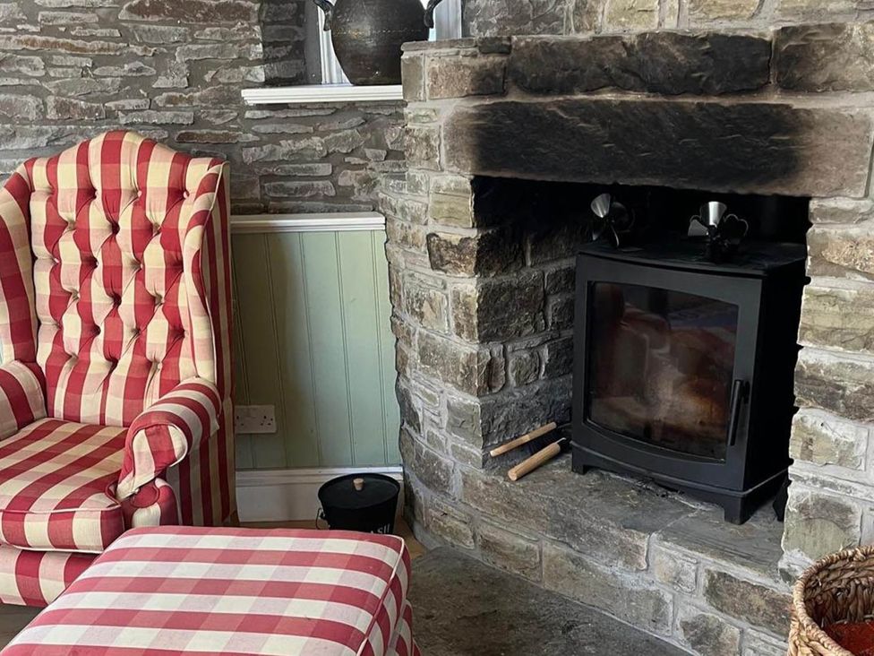 A living room with an armchair and fireplace at The Hills Farmhouse 6 Bed Sleeps 11 Pets Llanfilo near Talgarth