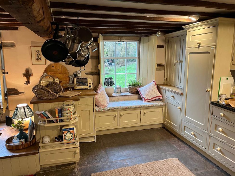 A kitchen with pots hanging and a window overlooking the garden at The Hills Farmhouse 6 Bed Sleeps 11 Pets Llanfilo near Talgarth