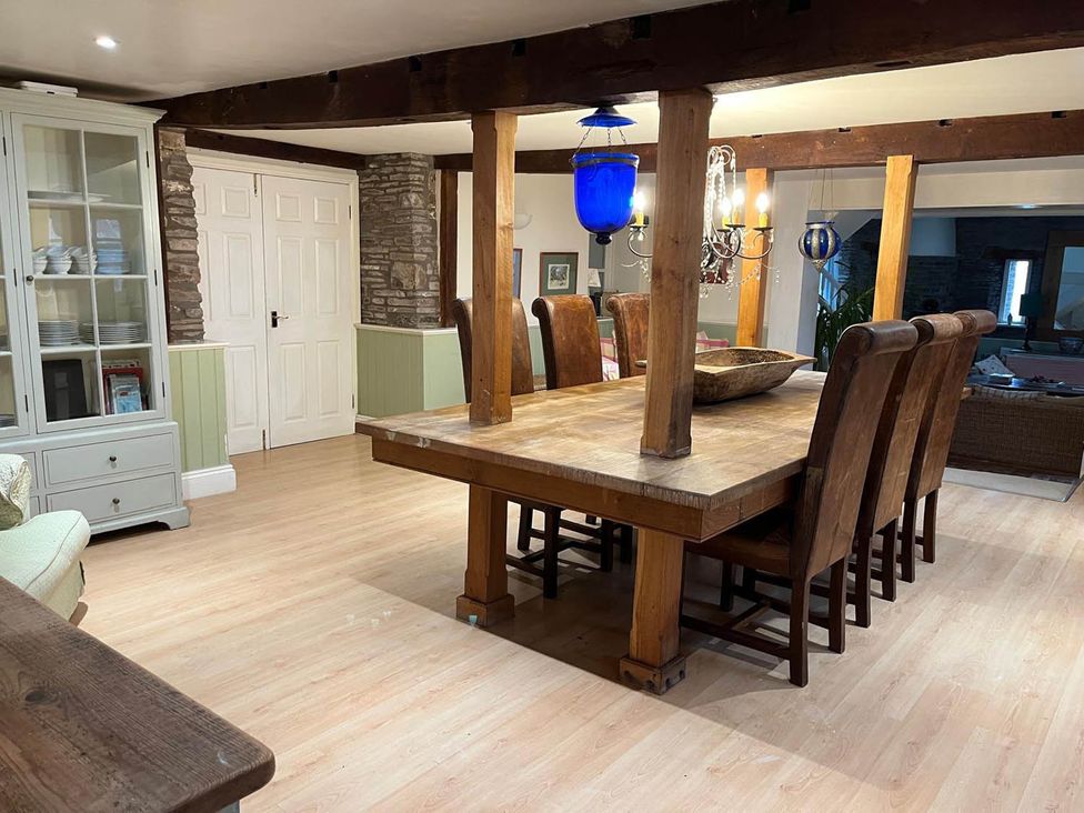A dining room with a large wooden table and chairs at The Hills Farmhouse 6 Bed Sleeps 11 Pets Llanfilo near Talgarth