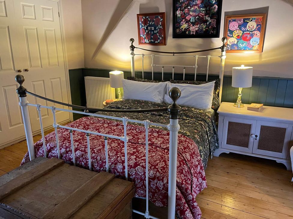 A bedroom with a bed, nightstand, and artwork at The Hills Farmhouse 6 Bed Sleeps 11 Pets in Llanfilo near Talgarth