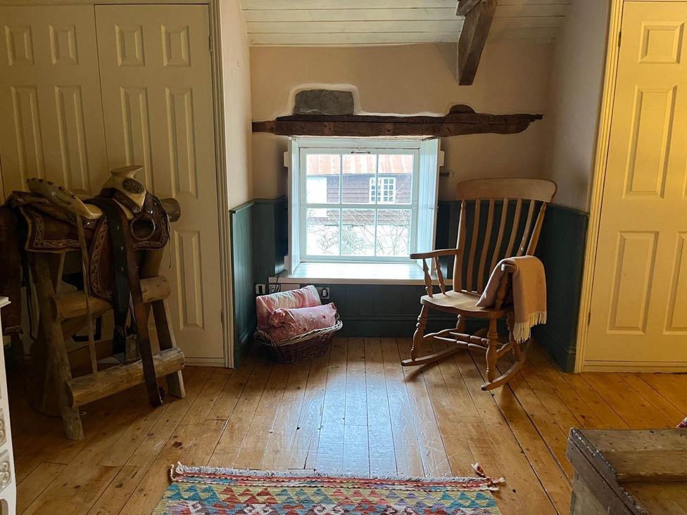 A sitting room with a rocking chair and saddle at The Hills Farmhouse 6 Bed Sleeps 11 Pets Llanfilo near Talgarth