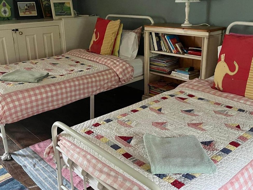 A bedroom with two beds and a bookshelf at The Hills Farmhouse 6 Bed Sleeps 11 Pets Llanfilo near Talgarth