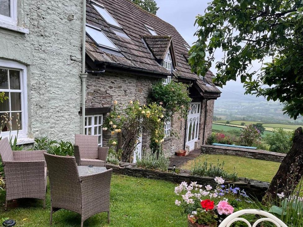 A garden with chairs and flowers at The Hills Farmhouse 6 Bed Sleeps 11 Pets in Llanfilo near Talgarth