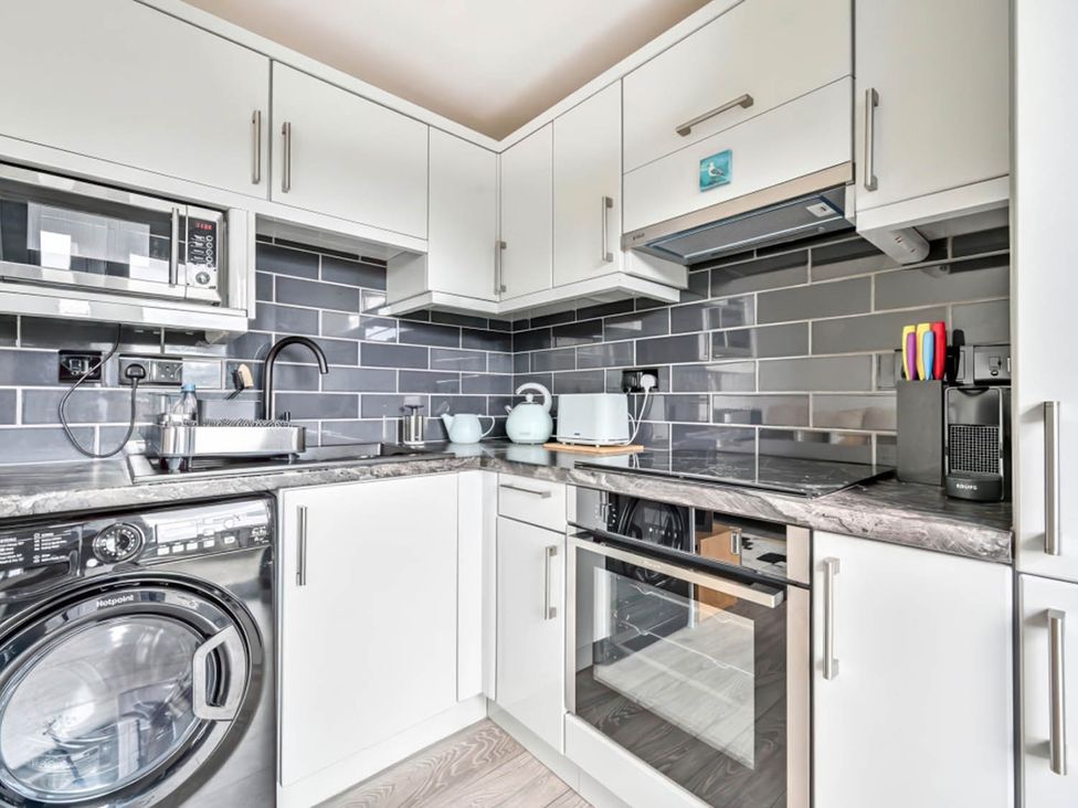 A kitchen with appliances and a washing machine at Torpoint Apartment Sleeps4 Seaside Parking Downderry