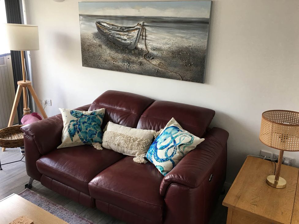 A living room with a red sofa and a lamp at Torpoint Apartment Sleeps4 Seaside Parking in Downderry