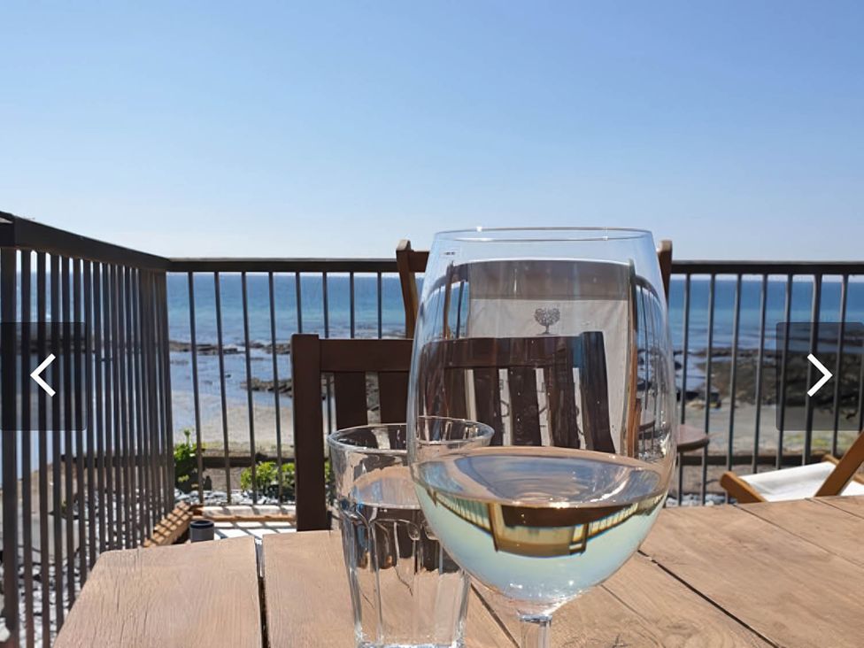 A glass of water and wine glass on a table with ocean view at Torpoint Apartment Sleeps4 Seaside Parking Downderry