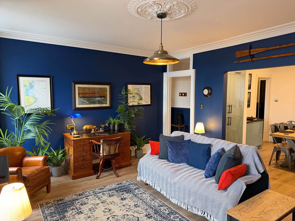 A living room with a sofa, desk, and plants at Seaview Apartment 2Bed on Anstruther Harbour in Anstruther