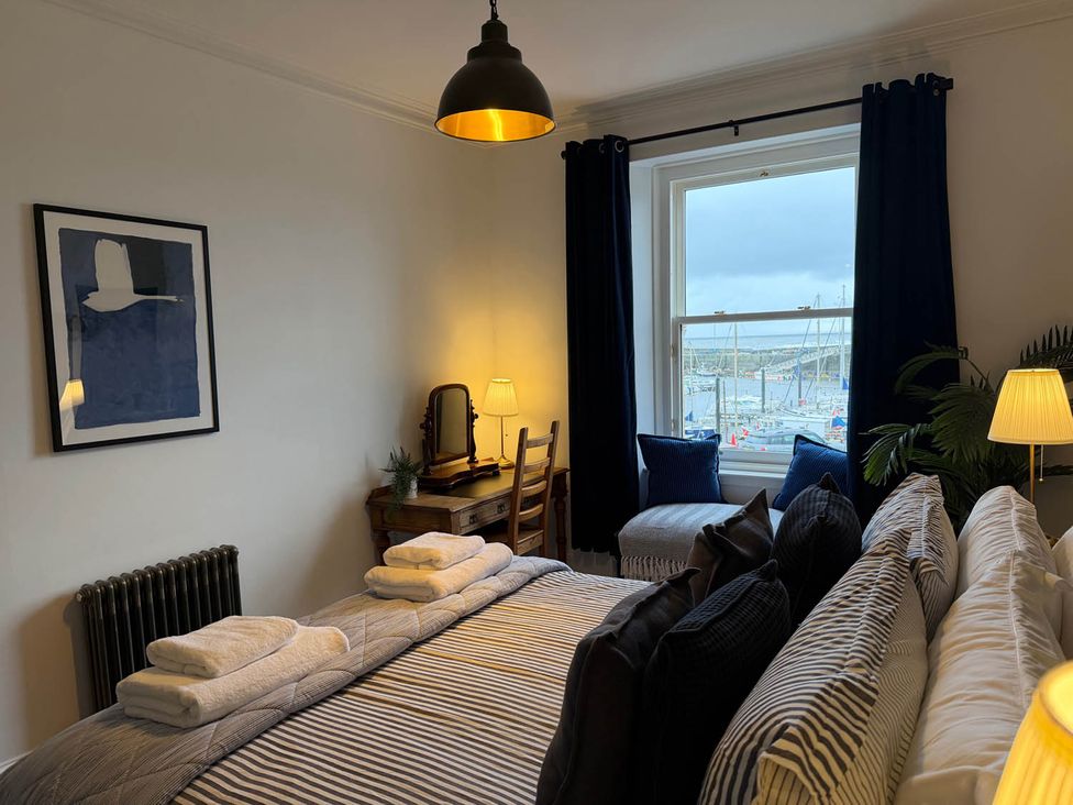 A bedroom with a bed and a table at Seaview Apartment 2Bed on Anstruther Harbour Anstruther