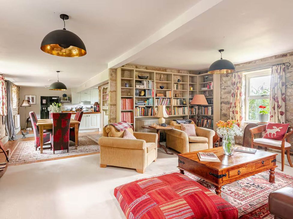 A living room with a dining table and bookshelves at Dowgill 3Bed Barn Sleeps 7 Hot Tub Parking Near Summerbridge