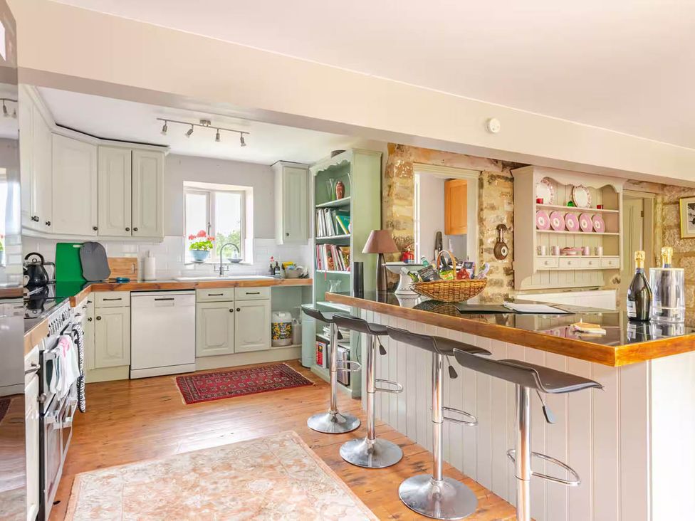 A kitchen with appliances and bar stools at Dowgill 3Bed Barn Sleeps 7 Hot Tub Parking Near Summerbridge