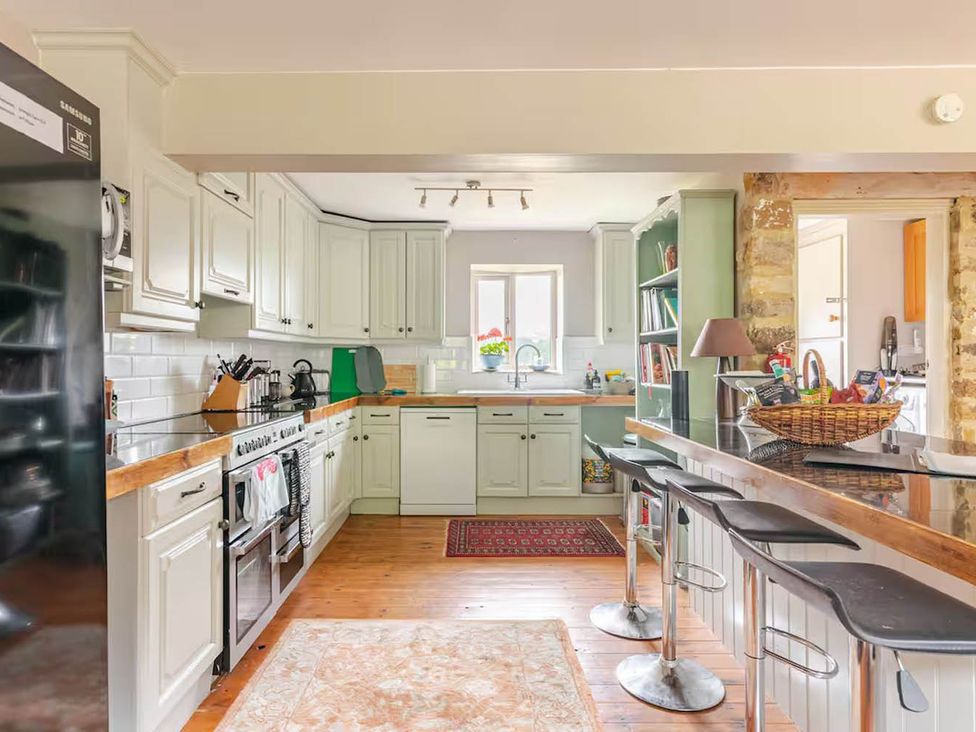 A kitchen with cabinets, appliances and bar stools at Dowgill 3Bed Barn Sleeps 7 Hot Tub Parking Near Summerbridge
