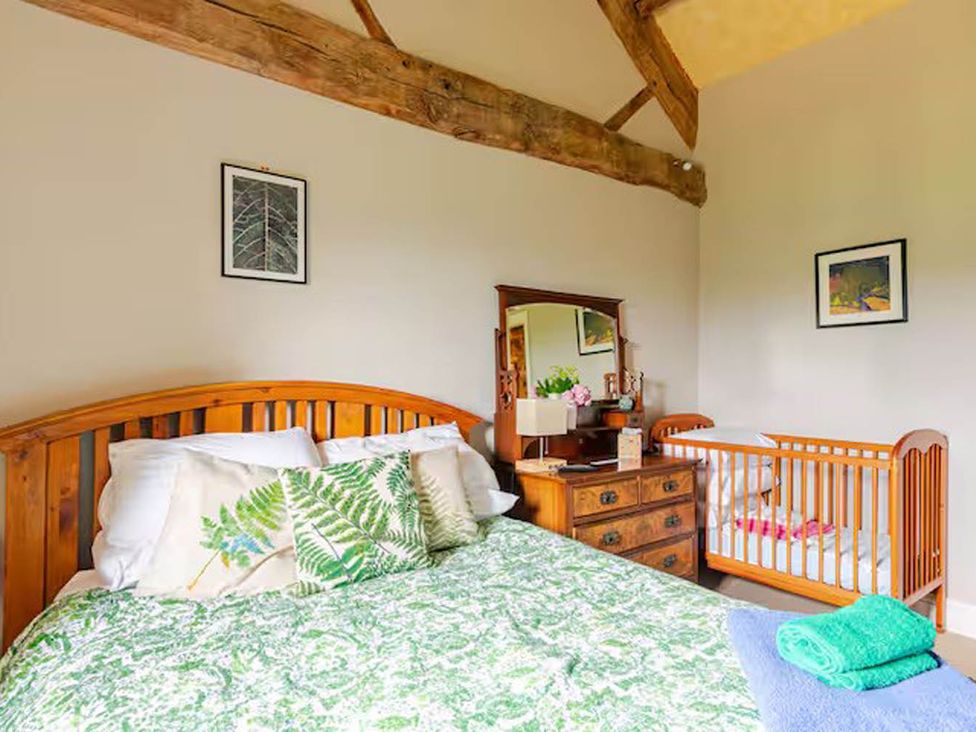 A bedroom with a bed and a baby crib at Dowgill 3Bed Barn Sleeps 7 Hot Tub Parking Near Summerbridge