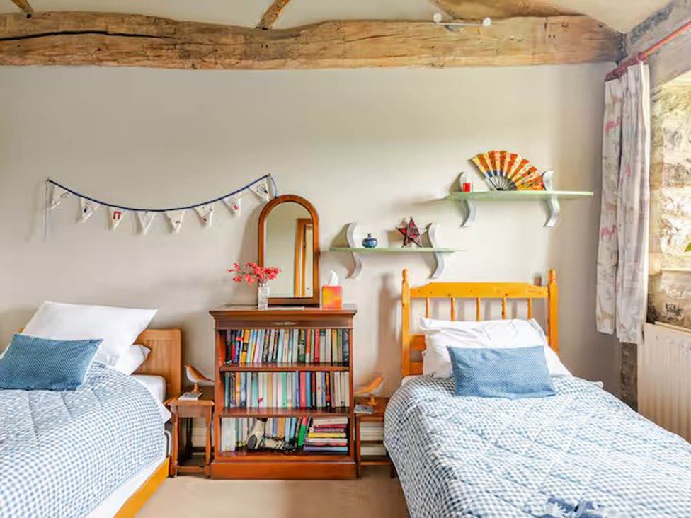 A bedroom with two beds, a bookshelf, and decorative items at Dowgill 3Bed Barn Sleeps 7 Hot Tub Parking Near Summerbridge