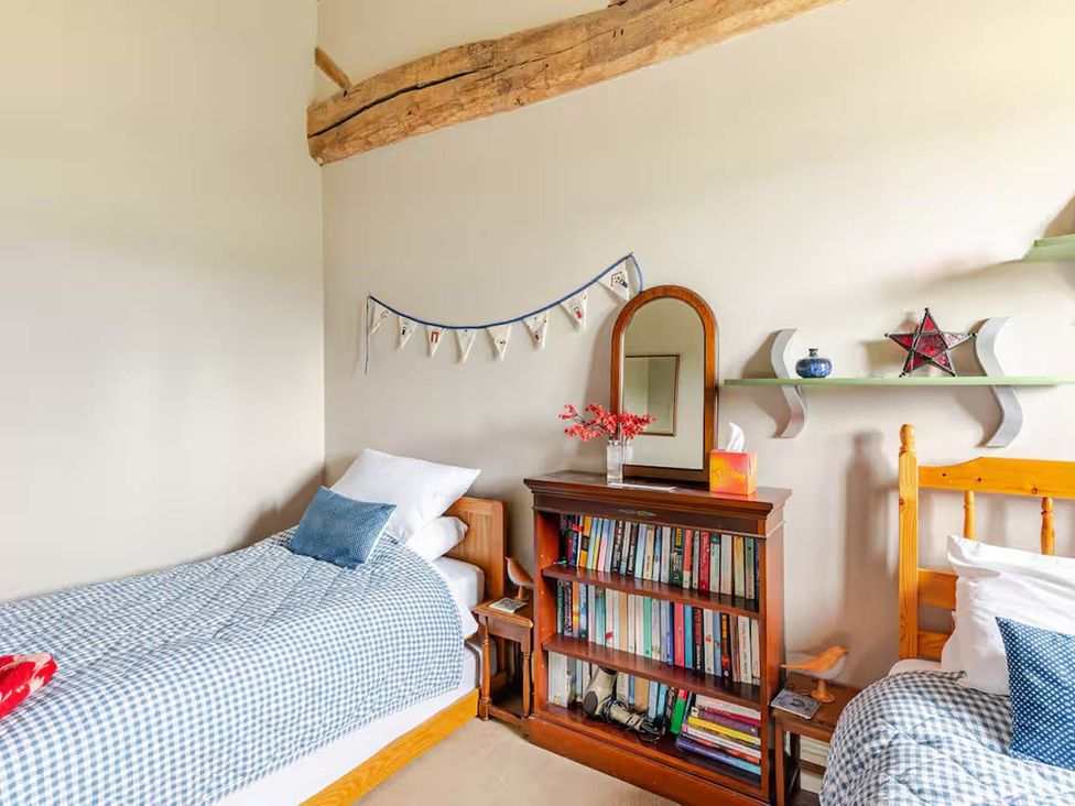A bedroom with two beds and a bookshelf at Dowgill 3Bed Barn Sleeps 7 Hot Tub Parking Near Summerbridge