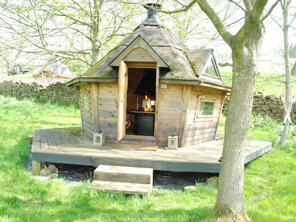 A wooden cabin with a deck and steps in a garden near Summerbridge at Dowgill 3Bed Barn Sleeps 7 Hot Tub Parking