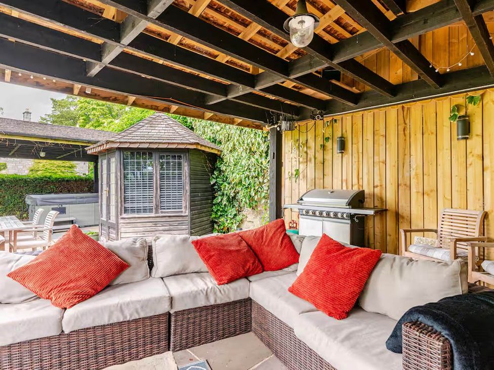 An outdoor seating area with a sofa and grill at Dowgill 3Bed Barn Sleeps 7 Hot Tub Parking Near Summerbridge
