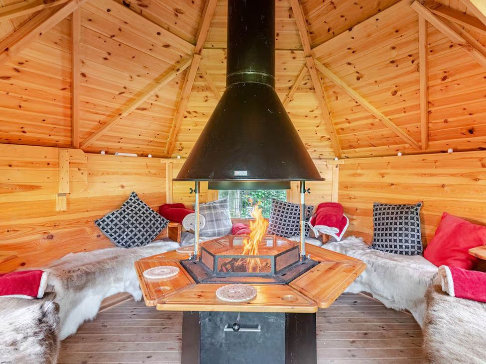 A seating area with a fireplace and wooden table at Dowgill 3Bed Barn Sleeps 7 Hot Tub Parking Near Summerbridge