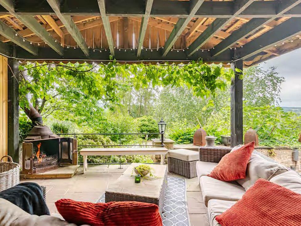 An outdoor living area with a fireplace and seating at Dowgill 3Bed Barn Sleeps 7 Hot Tub Parking near Summerbridge