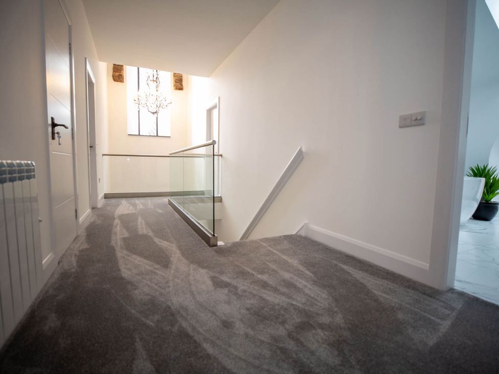 A hallway with a staircase and light fixture at Stunning 3 Bed Converted Village Hall Near Kelso Nenthorn near Kelso