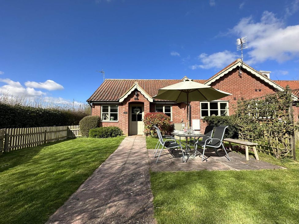 A garden with a table, chairs, and umbrella at Cottage Sleep 4 Pet Friendly Enclosed Garden, Rollesby, near Scratby