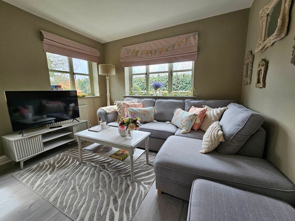 A living room with a sofa and television at Cottage Sleep 4 Pet Friendly Enclosed Garden in Rollesby, near Scratby