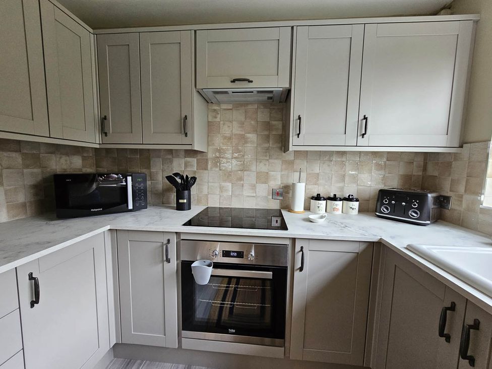 A kitchen with cabinets, a stove, microwave, and toaster at Cottage Sleep 4 Pet Friendly Enclosed Garden in Rollesby, near Scratby