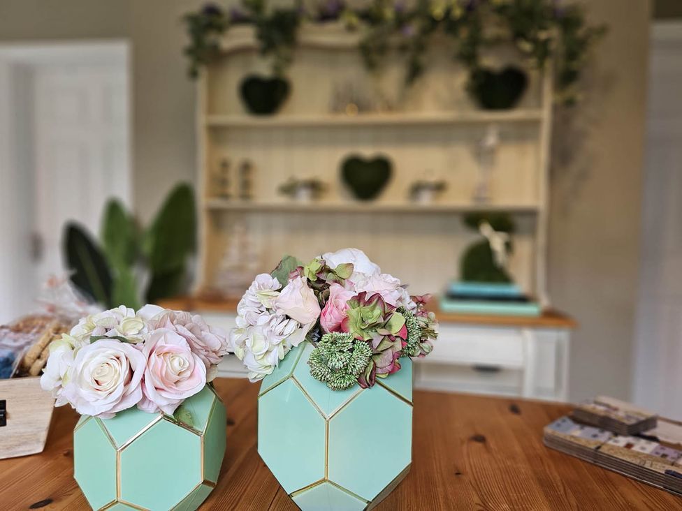 A flower arrangement in geometric vases on a wooden table at Cottage Sleep 4 Pet Friendly Enclosed Garden in Rollesby, near Scratby