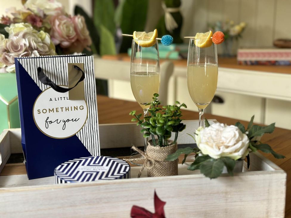 A table set with drinks, a gift bag, and decorative items at Cottage Sleep 4 Pet Friendly Enclosed Garden, Rollesby, near Scratby