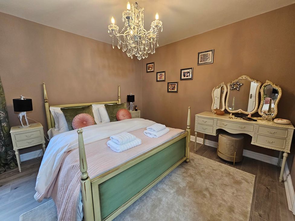 A bedroom with a bed, bedside tables, and a vanity at Cottage Sleep 4 Pet Friendly Enclosed Garden, Rollesby, near Scratby