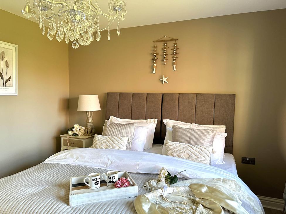 A bedroom with a bed and chandelier at Cottage Sleep 4 Pet Friendly Enclosed Garden, Rollesby, near Scratby