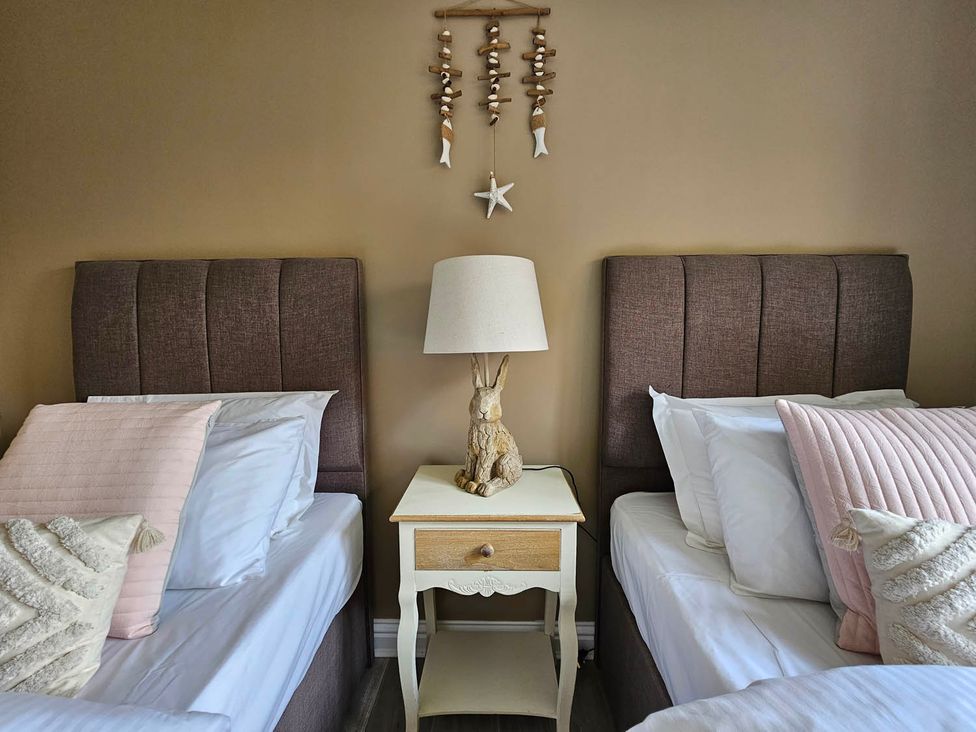 A bedroom with two beds and a bedside table at Cottage Sleep 4 Pet Friendly Enclosed Garden, Rollesby, near Scratby