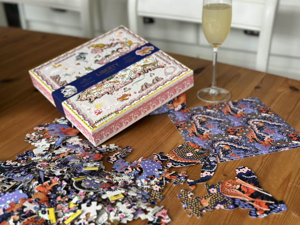 Puzzle pieces scattered on a table with a box and a glass at Cottage Sleep 4 Pet Friendly Enclosed Garden in Rollesby, near Scratby
