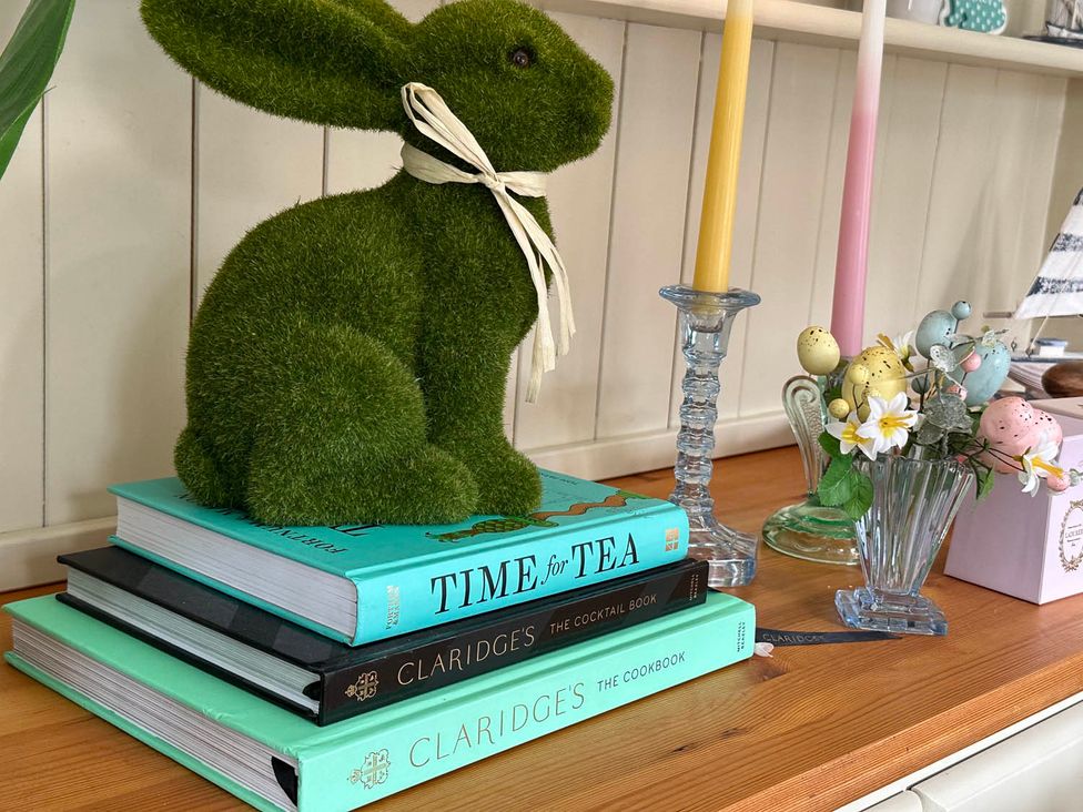 A decorative arrangement with a rabbit statue, books, and flowers at Cottage Sleep 4 Pet Friendly Enclosed Garden, Rollesby, near Scratby