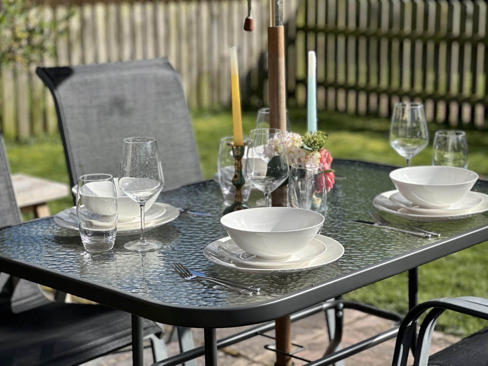 An outdoor dining area with a table set for a meal at Cottage Sleep 4 Pet Friendly Enclosed Garden, Rollesby, near Scratby