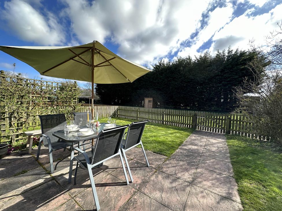 A garden with a table and chairs under an umbrella at Cottage Sleep 4 Pet Friendly Enclosed Garden Rollesby, near Scratby
