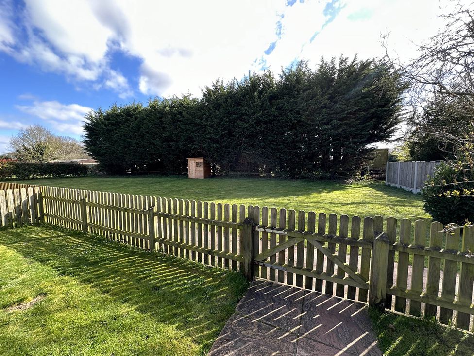 A garden with a fence, gate, grassy area, trees, and a shed at Cottage Sleep 4 Pet Friendly Enclosed Garden, Rollesby, near Scratby