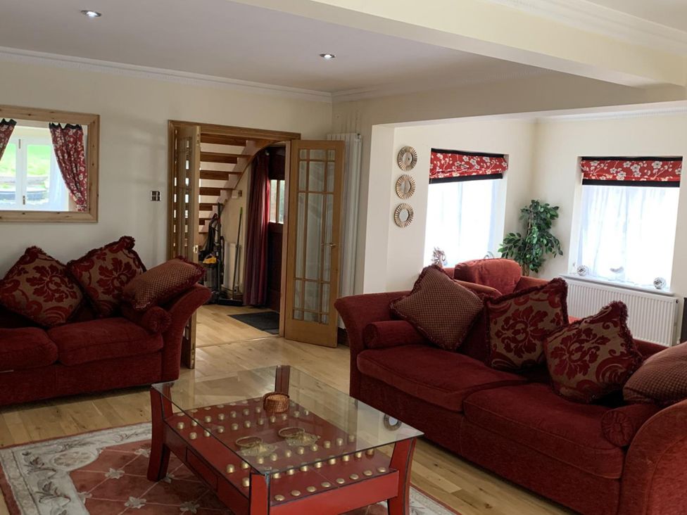 A living room with red sofas and a glass coffee table at 2Bedroom Cottage with 2 Ensuites Sleeps 6 Wifi Near Rye