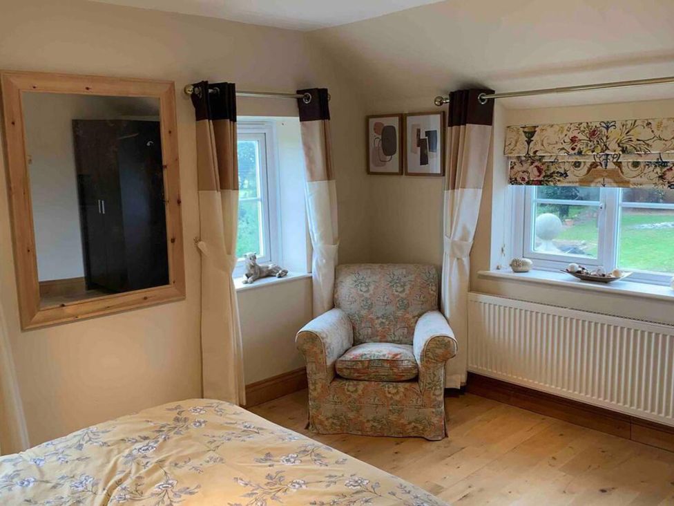 A bedroom with a bed, mirror, wardrobe, chair, and window at 2Bedroom Cottage with 2 Ensuites Sleeps 6 Wifi Near Rye