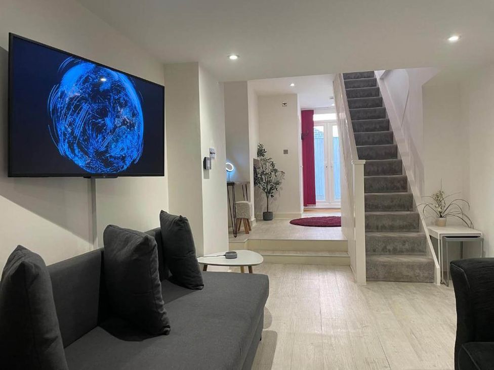 A living room with a television and a staircase at Family Friendly Apt Sleeps 6 Station Close in Royal Tunbridge Wells