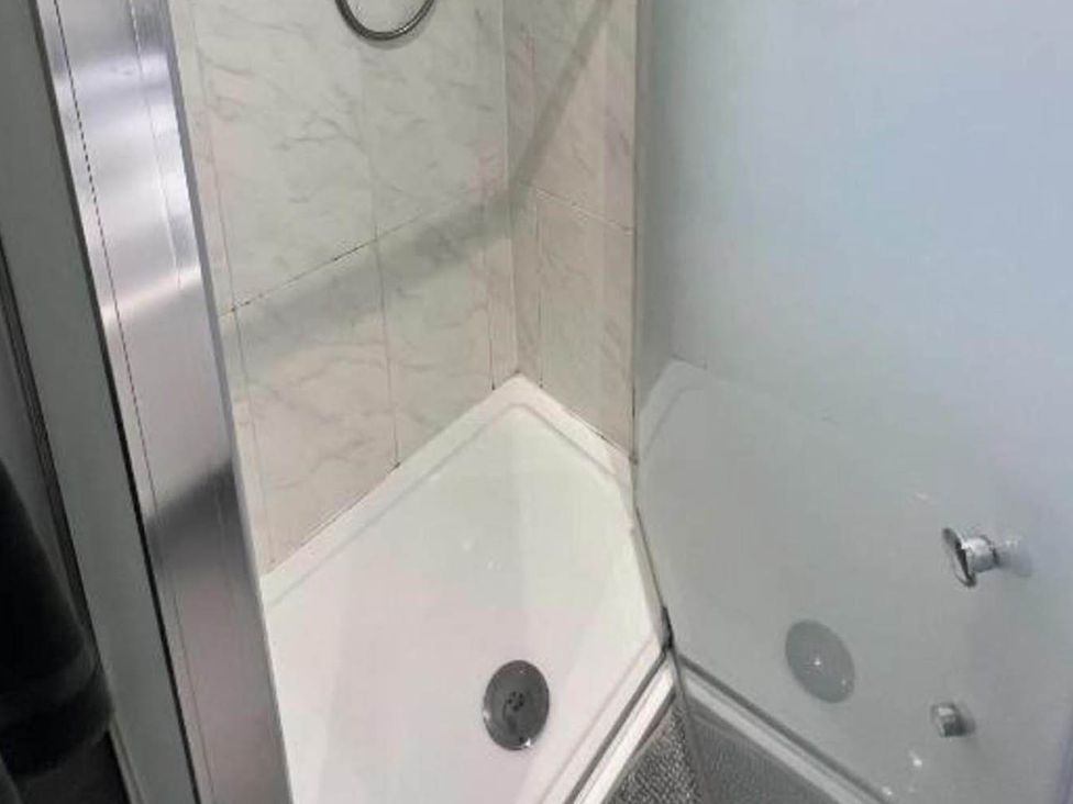 A shower stall with a drain and wall tiles at Family Friendly Apt Sleeps 6 Station Close Royal Tunbridge Wells