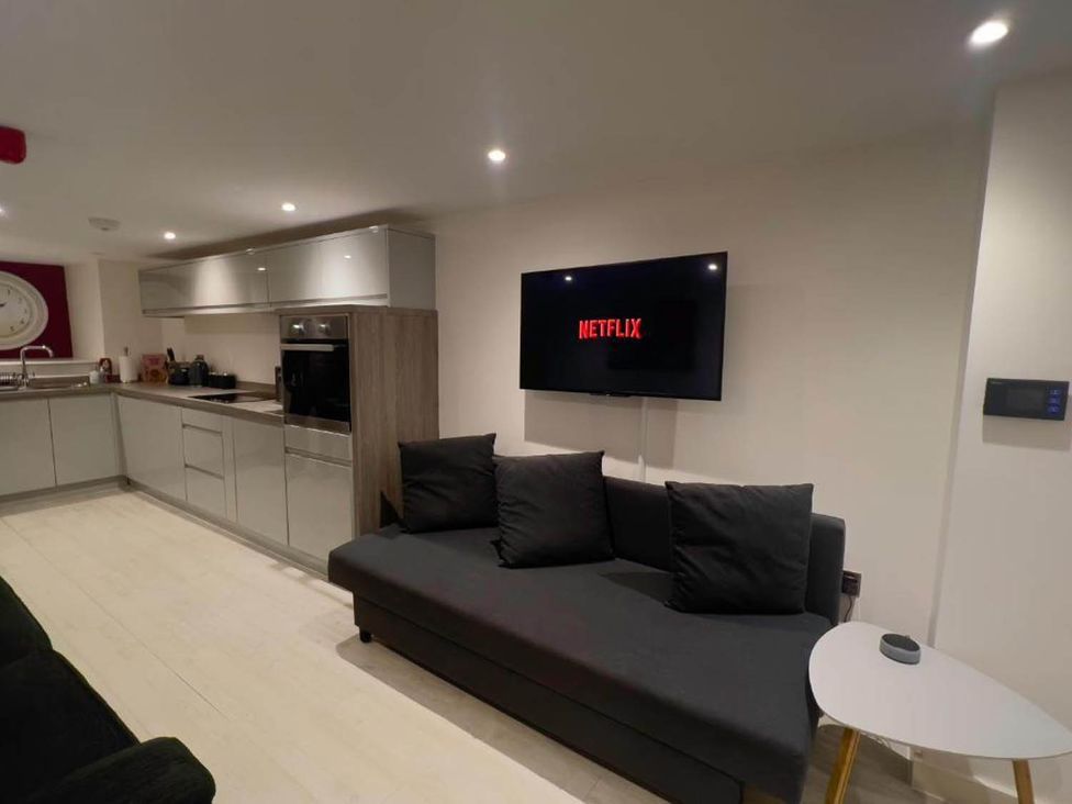 A living room with a sofa and a television displaying Netflix at Family Friendly Apt Sleeps 6 Station Close in Royal Tunbridge Wells
