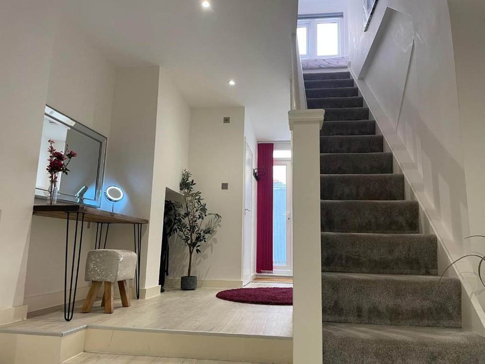 A hallway with a staircase and a mirror desk in Family Friendly Apt Sleeps 6 Station Close Royal Tunbridge Wells
