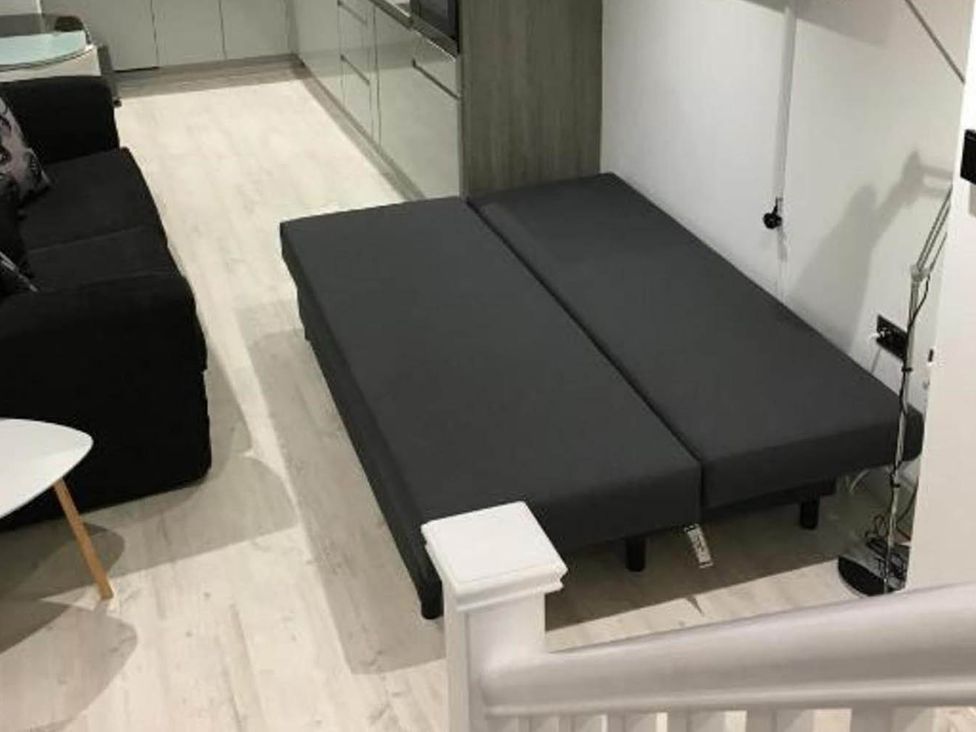 A living room with a black sofa and a gray mattress at Family Friendly Apt Sleeps 6 Station Close in Royal Tunbridge Wells